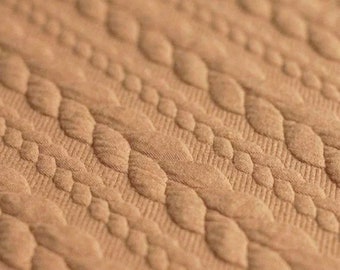 Tejido de sudadera texturizado de punto trenzado color camello - 150 cm de ancho. Tejido de jersey jacquard suave y lujoso. Se vende por medio metro. Color beige natural.