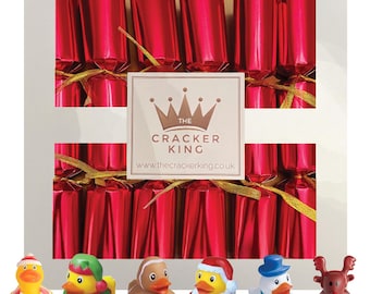 Può includere: Immagine a tema natalizio con cracker rossi con nastri dorati e sei paperelle di gomma. Le paperelle sono vestite con costumi festivi, tra cui un Babbo Natale, un elfo e un pupazzo di neve. Il logo Cracker King è visibile.