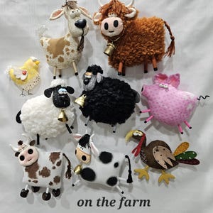 May include: A collection of handmade farm animal figurines, including cows, sheep, a pig, a turkey, and a chicken. The figurines are made of fabric and have detailed features. The text "on the farm" is at the bottom.