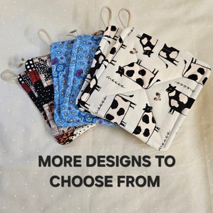 May include: Four different pot holders with various patterns. One pot holder features a black and white cow print with the word "moo" repeated on the fabric. Another pot holder has a blue floral pattern. A third pot holder has a black and white checkered pattern with red accents. The fourth pot holder has a red, black, and white patchwork pattern. The text "MORE DESIGNS TO CHOOSE FROM" is at the bottom of the image.