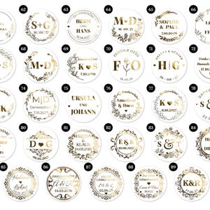 May include: A collection of white circular stickers with gold text and decorative borders. Each sticker features names, initials, and dates, likely for a wedding or special event. The designs vary, including floral and leaf motifs.