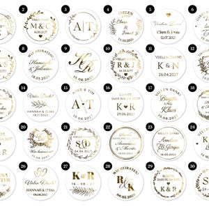 May include: A collection of gold and white wedding favor stickers with various names, dates, and initials. The stickers are round and feature floral and leaf designs. Some include the text "Vielen Dank!"