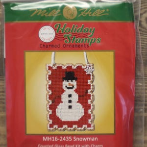 May include: A packaged craft kit featuring a snowman design. The kit is labeled "Holiday Stamps Charmed Ornaments" and includes a counted glass bead kit with a charm. The design size is 2.25" wide by 3.25" high.