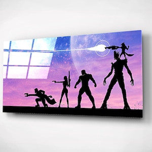 Könnte beinhalten: Silhouetten von fünf Charakteren aus der Guardians of the Galaxy-Filmreihe vor einem lila und blauen Weltraumhintergrund. Die Charaktere stehen in einer Reihe, nach vorne gerichtet, mit einem weißen Lichtstrahl, der aus der Hand des rechtsesten Charakters schießt.