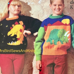 May include: Two children wearing colorful knit sweaters with dinosaur designs. The girl's sweater is black with a yellow dinosaur, and the boy's sweater is multi-colored with a green dinosaur. The text "double knit" is visible in the top right corner of the image.