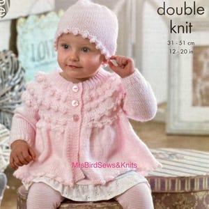 Op de afbeelding: Een baby in een lichtroze gebreide outfit, bestaande uit een muts, vest en babyslofjes. Het vest heeft een gerimpelde kraag en knoopsluiting. De muts en slofjes hebben een geschulpte rand. De tekst "double knit" is zichtbaar, met afmetingen van 31-51 cm.
