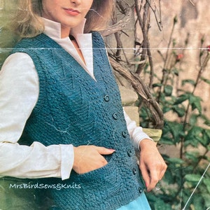 May include: A teal blue knitted waistcoat with a cable knit pattern and six buttons down the front. The waistcoat has a pocket on the left side.  MrsBirdSewsgKnits is printed on the bottom of the image.