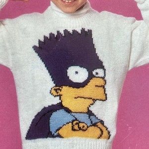 May include: A white knitted sweater with a cartoon image of Bart Simpson from The Simpsons. The sweater has a crew neck and long sleeves.