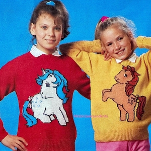 May include: Two children wearing matching knit sweaters. One is red with a white and blue pony design, the other yellow with a brown and red pony design. Both sweaters have white collars. The background is blue.