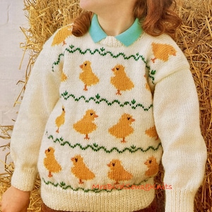 May include: A white knitted sweater with a pattern of yellow chicks and green leaves. The sweater has long sleeves and a crew neck.
