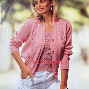 Puede incluir: Un cárdigan de punto rosa y una blusa a juego con un patrón de encaje en forma de diamante. El cárdigan tiene cierre de botones y la blusa es sin mangas.