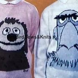 May include: Two knitted sweaters with cartoon animal designs. The pink sweater features a black dog with a brown nose and big eyes. The white sweater features a blue bird with a black beak and eyebrows.