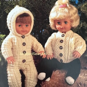 May include: Two dolls wearing hand-knitted outfits. One doll is in a hooded jumpsuit, the other in a sweater, both in cream-colored yarn with brown buttons. The dolls are sitting on a log. The text "double knit" is at the top.