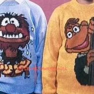 May include: Two knitted sweaters featuring characters from The Muppets. The sweater on the left is light blue with a brown and orange image of Animal, the drummer. The sweater on the right is yellow with a brown and orange image of Scooter, the Muppet who works in the control room.