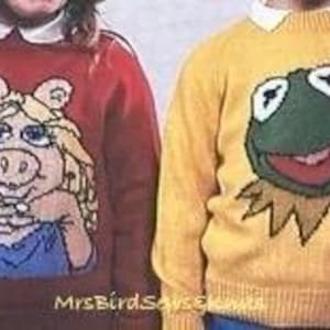 May include: Two knitted sweaters featuring cartoon characters. The sweater on the left is red with a pink pig wearing a blue dress. The sweater on the right is yellow with a green frog wearing a yellow shirt.