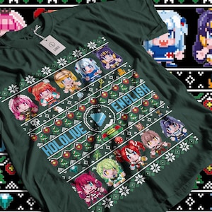 Può includere: Una maglietta verde con un design a tema natalizio che presenta un'immagine pixelata di un gruppo di personaggi anime. Il design include il testo "HOLOLIVE ENGLISH" e un logo blu e bianco.