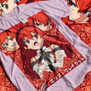 Könnte beinhalten: Ein helllila T-Shirt mit einer Anime-Illustration. Das Design zeigt eine Figur mit roten Haaren und blauen Augen, umgeben von dekorativen roten Mustern. Der Text "Mushoku Tensei" und japanische Schriftzeichen sind ebenfalls zu sehen.