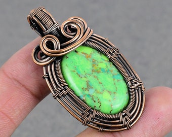 May include: A copper wire wrapped pendant featuring a green and gold oval gemstone.