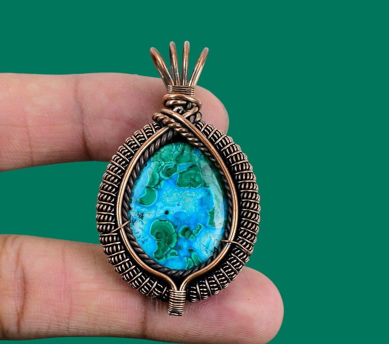 May include: A copper wire wrapped pendant featuring a green and blue malachite stone. The pendant has a detailed wire design and is perfect for adding a touch of nature to any jewelry collection.