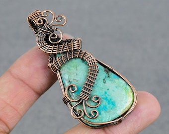 May include: A turquoise gemstone pendant wrapped in copper wire with intricate designs. The pendant has a teardrop shape and is set in a woven copper wire frame.