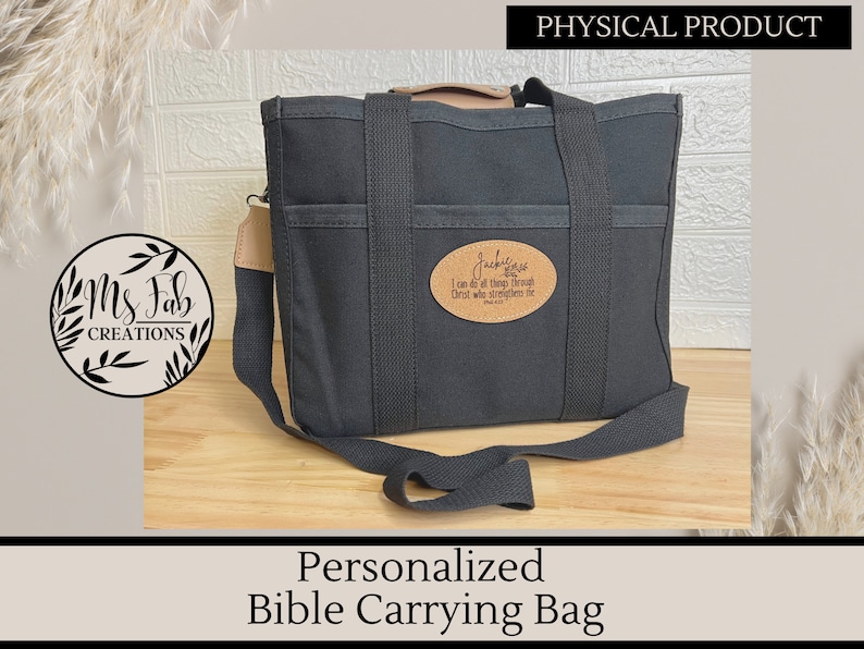 Op de afbeelding: Zwarte canvas tas om de Bijbel te dragen met een bruine leren band en een ingebrand opschrift met de tekst "Ik kan alles door Christus, die mij kracht geeft." Filippenzen 4:13