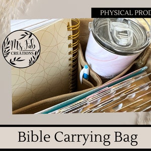 May include: A beige canvas bag with multiple pockets and compartments. The bag is filled with a spiral bound notebook, a tumbler, a pen, and a stack of books. The bag is labeled "Bible Carrying Bag".