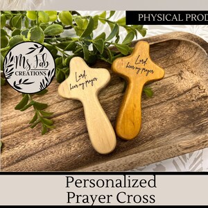 May include: Two wooden prayer crosses with the text "Lord, hear my prayer" engraved on them. The crosses are on a wooden tray.
