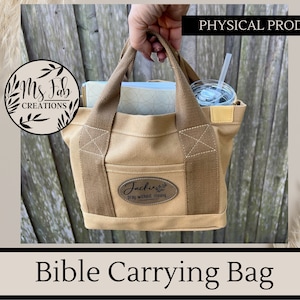 May include: A tan canvas Bible carrying bag with brown straps and a brown leather patch that says "Jackie's Pray Without Ceasing".