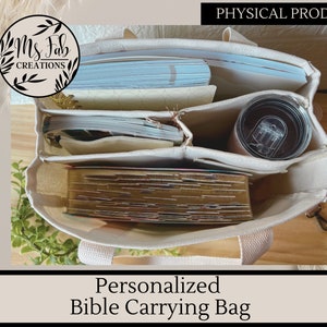 Op de afbeelding: Een witte canvas draagtas met meerdere vakken om boeken en andere spullen in te dragen. De tas heeft een ritssluiting en twee handvatten. De tas is gelabeld met "Ms. Fab Creations" en "Gepersonaliseerde Bijbeldraagtas".