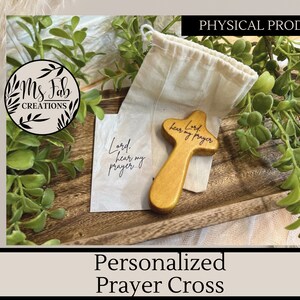 May include: A wooden prayer cross with the words "Lord hear my prayer" engraved on it. The cross is in a small burlap bag and is sitting on a wooden tray.