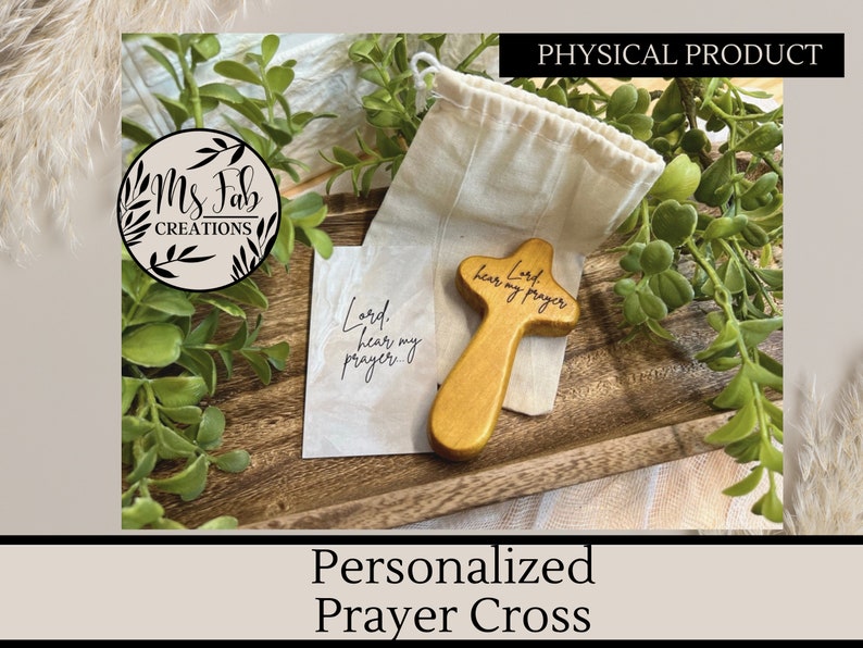 May include: A wooden prayer cross with the words "Lord hear my prayer" engraved on it. The cross is in a small burlap bag and is sitting on a wooden tray.