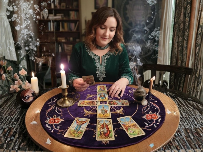 May include: A woman in a green velvet dress is reading tarot cards on a round table. The table is covered with a purple cloth with a tarot card layout. Lit candles and incense add to the mystical atmosphere. The scene is set in a room with a bookshelf.