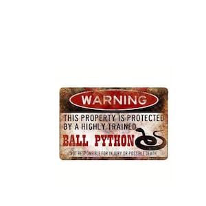 Könnte beinhalten: Ein rostiges Metallschild mit einer Warnung vor einer Königspython. Das Schild lautet "WARNING THIS PROPERTY IS PROTECTED BY A HIGHLY TRAINED BALL PYTHON NOT RESPONSIBLE FOR INJURY OR POSSIBLE DEATH".