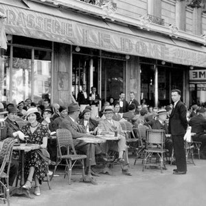 May include: A black and white photo of people sitting at tables outside a cafe. The cafe is called "Le Dome" and has a sign that says "Brasserie", which is a French word for a type of restaurant. The people are dressed in 1920s clothing and are enjoying their time at the cafe.