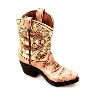 May include: A pink cowboy boot with gold embroidery and a black heel.