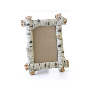 May include: A rustic picture frame made from birch bark with a natural wood finish. The frame has a rectangular shape and is designed to hold a standard-sized photograph.