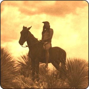 Puede incluir: Un hombre nativo americano con un tocado cabalga un caballo a través de un campo de hierba alta. El cielo es de un color naranja cálido, y el hombre y el caballo están silueteados contra la puesta de sol.