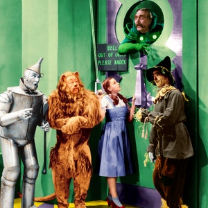 May include: A group of four characters from the Wizard of Oz stand in front of a green door. Dorothy, the Scarecrow, the Tin Man, and the Cowardly Lion are all looking at the door. The sign on the door reads "Bell Out of Order Please Knock".