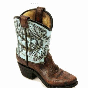 Pode incluir: Uma bota de cowboy marrom com um design estampado em azul claro e branco. A bota tem uma ponta pontiaguda e um salto alto.
