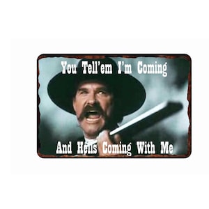 May include: A vintage-style metal sign featuring a man in a cowboy hat with a serious expression. The sign reads "You Tell'em I'm Coming And Hell's Coming With Me".