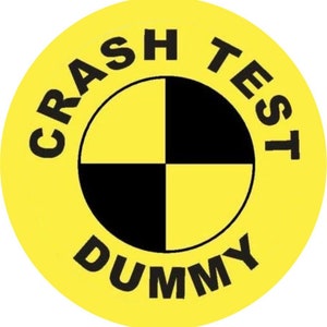 May include: Yellow circle with black text that reads "Crash Test Dummy" and a black and yellow checkered target in the center.