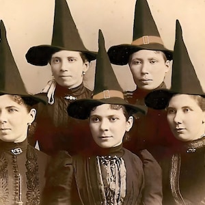 May include: Five women wearing black witch hats with pointed tops and wide brims. The women are dressed in dark clothing and have serious expressions on their faces.