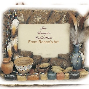 May include: A rustic wooden picture frame with a Native American theme. The frame is decorated with feathers, beads, and small pottery pieces. The frame has a beige mat and a clear glass front. The text "The Unique Collection From Renee's Art" is printed on the mat.