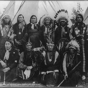 May include: A group of Native American men wearing traditional clothing and headdresses. They are standing in front of a tent.