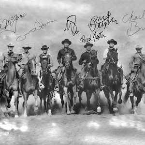 以下が含まれることがあります： 砂ぼこりが舞う野原を、馬に乗った6人の男性が駆ける白黒写真。男性たちはカウボーイハットをかぶり、ウエスタンスタイルの服装をしている。写真はスティーブ・マックイーン、ジェームズ・コバーン、チャールズ・ブロンソン、ブラッド・デクスターのサイン入りである。