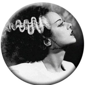 May include: Black and white photograph of a woman with a hairstyle reminiscent of Frankenstein's monster. Her hair is styled in a series of waves and curls, and she is looking up and to the right.