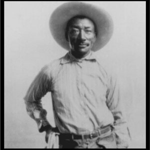 Puede incluir: Un retrato en blanco y negro de un hombre con un sombrero de ala ancha y una camisa abotonada. Está mirando directamente a la cámara.