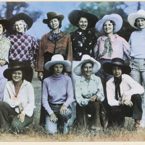 May include: A vintage photograph features a group of women in various outfits, including blouses, sweaters, and button-down shirts. They are wearing wide-brimmed hats in different colors. The women are standing and kneeling in a grassy area.