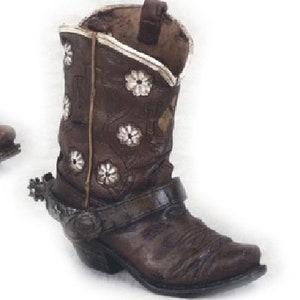 May include: A brown cowboy boot with a white floral design and a silver spur. The boot has a pointed toe and a low heel.