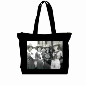 Può includere: Borsa tote in tela nera con una fotografia vintage di quattro donne che indossano cappelli da cowboy e abiti. Le donne sono in piedi davanti a un edificio.